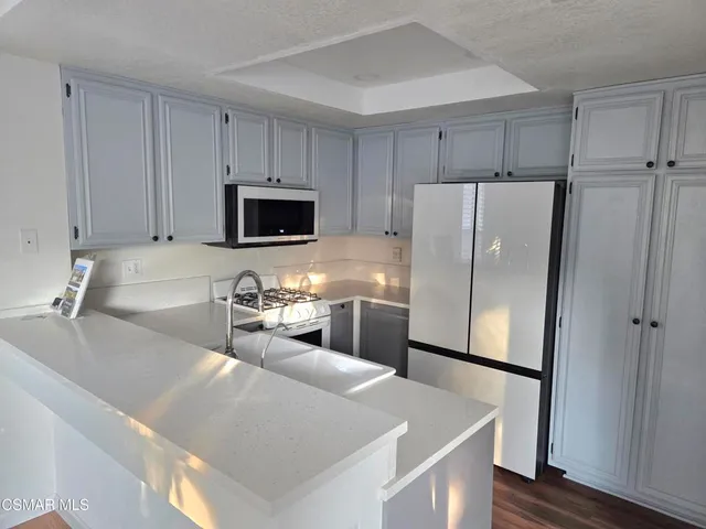 a kitchen with stainless steel appliances a refrigerator a sink a stove a microwave and wooden cabinets