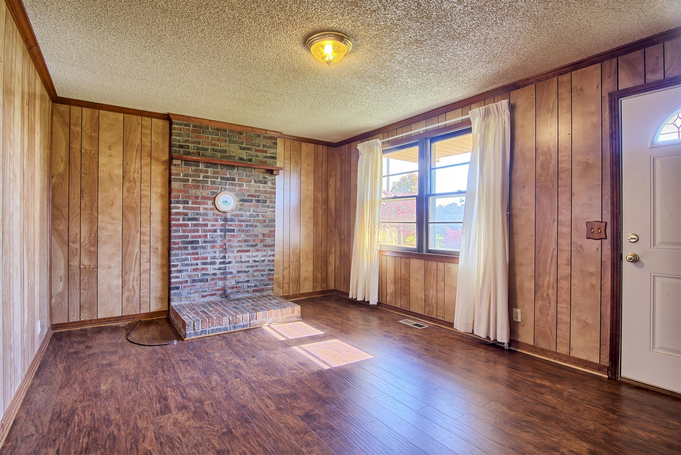 7487 Deer Ridge Road Primm Springs, TN 38476 - Photo 8 of 13 an empty room with wooden floor and windows with curtains
