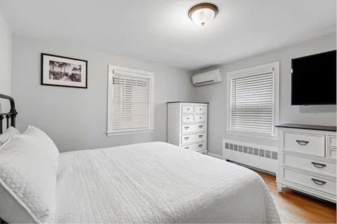 a bedroom with a bed and a flat tv screen on dresser