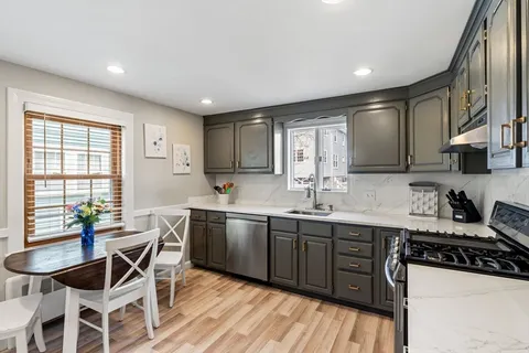 a kitchen with stainless steel appliances granite countertop wooden floor a stove a sink dishwasher and cabinets with wooden floor