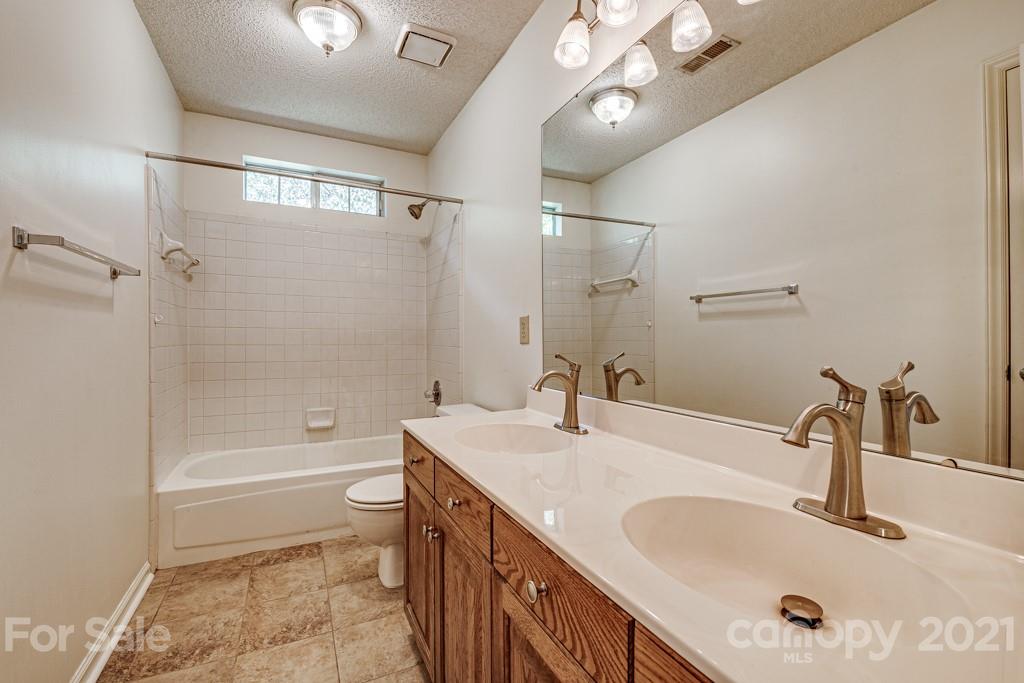 4516 Brownes Ferry Road Charlotte, NC 28269 - Photo 27 of 32 a bathroom with a granite countertop sink a toilet a mirror and shower