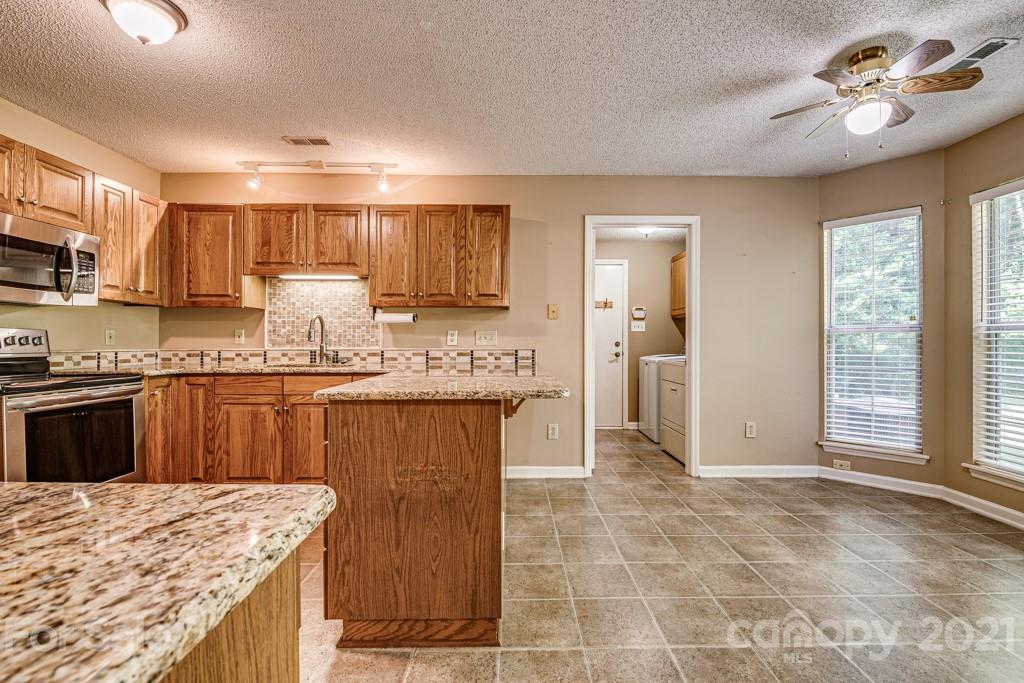 4516 Brownes Ferry Road Charlotte, NC 28269 - Photo 6 of 32 a kitchen with kitchen island granite countertop a stove a sink a refrigerator and a granite counter tops with white cabinets