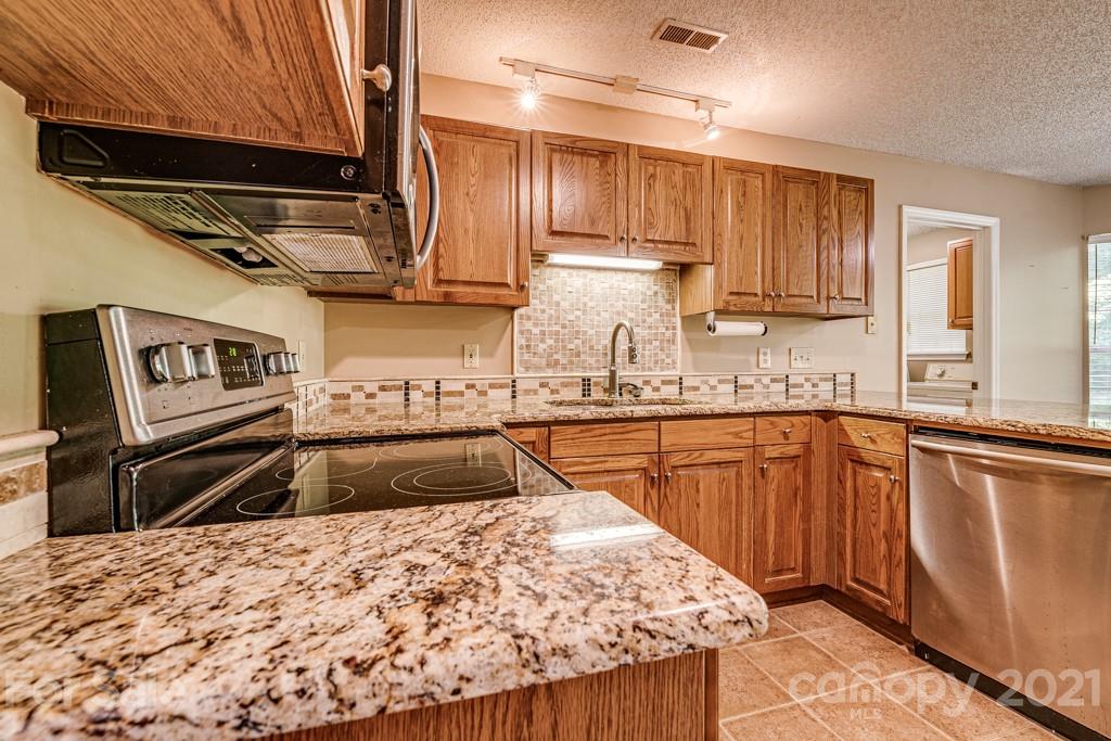 4516 Brownes Ferry Road Charlotte, NC 28269 - Photo 7 of 32 a kitchen with kitchen island granite countertop a sink and wooden cabinets