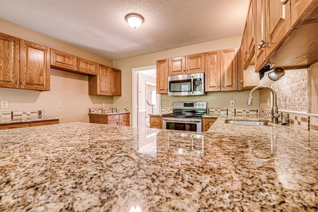 4516 Brownes Ferry Road Charlotte, NC 28269 - Photo 9 of 32 a kitchen with granite countertop a stove a sink and a microwave