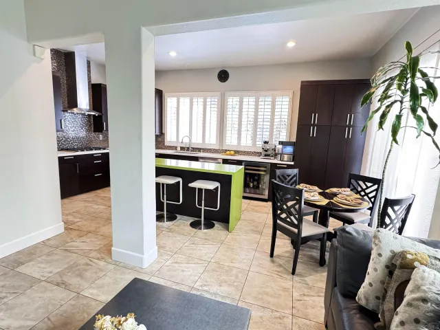 a kitchen with stainless steel appliances granite countertop a stove top oven a refrigerator a dining table and chairs with wooden floor