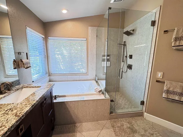 a bathroom with a granite countertop sink a bathtub and shower