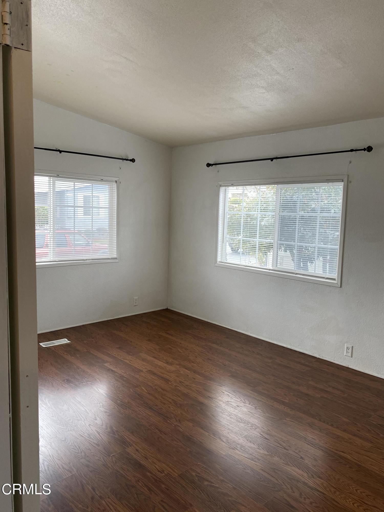 1853 Ives Avenue, Unit 151 Oxnard, CA 93033 - Photo 2 of 11 an empty room with wooden floor and windows