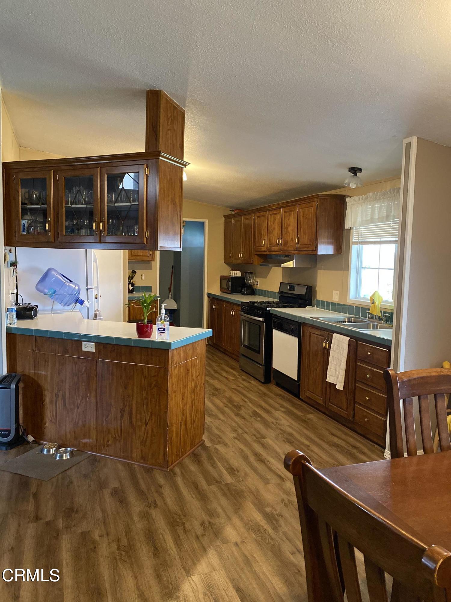 1853 Ives Avenue, Unit 151 Oxnard, CA 93033 - Photo 5 of 11 a kitchen with stainless steel appliances granite countertop a refrigerator a stove top oven and a sink
