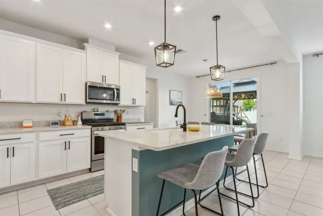 a kitchen with stainless steel appliances granite countertop a sink a stove a dining table and chairs