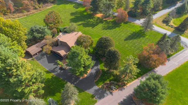 an aerial view of residential house with outdoor space and trees all around