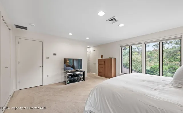a bedroom with a large bed and a flat tv screen