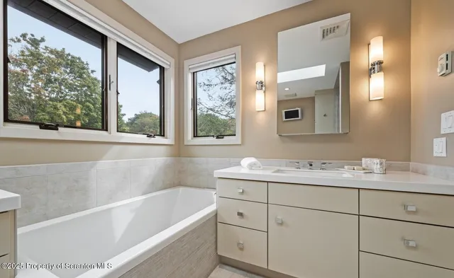 a bathroom with a bathtub sink and mirror