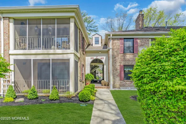a view of a house with a large windows and a yard with plants and a large tree