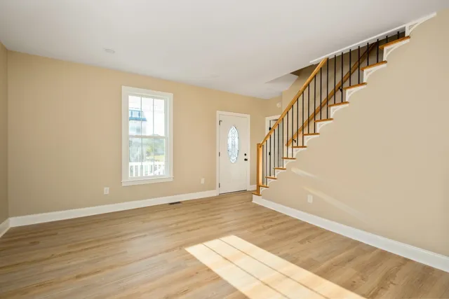 a view of an empty room with window and wooden floor