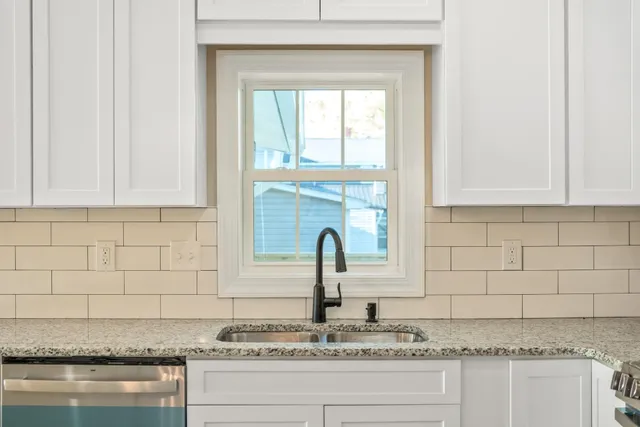 a kitchen with granite countertop white cabinets and window