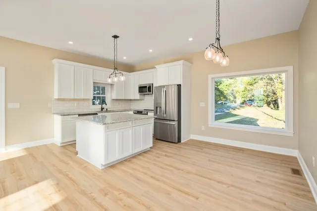 a kitchen with white cabinets and window