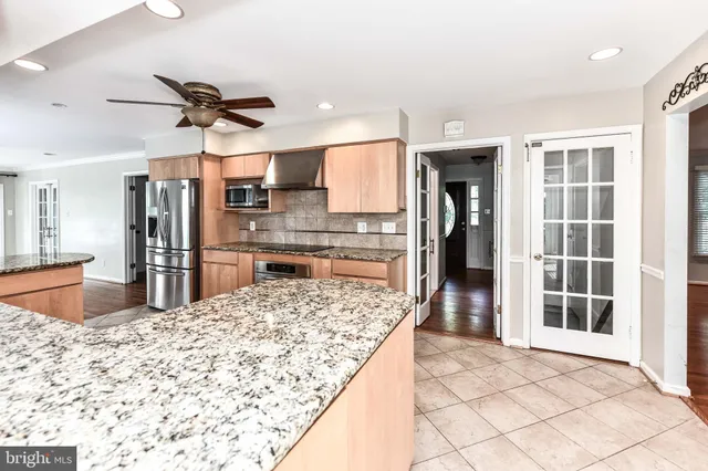 a kitchen with stainless steel appliances kitchen island granite countertop a refrigerator and a sink