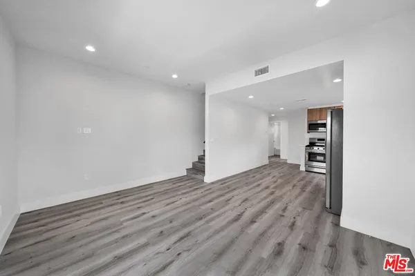 a view of a big room with wooden floor and a kitchen