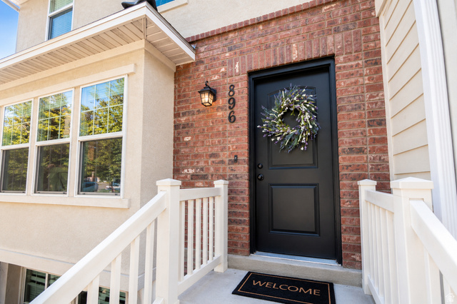 896 Cres Drive South Mapleton, UT 84664 - Photo 2 of 32 Front entry featuring a paneled black door, brick facade, stucco siding, multi-paned windows, and white porch railings