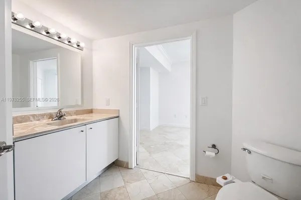 a en suite bathroom with a granite countertop sink mirror and toilet