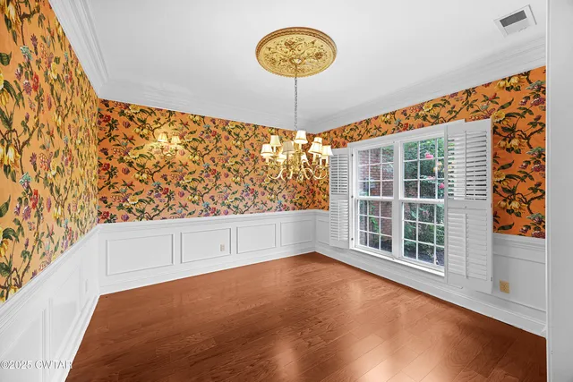 a view of an empty room with a window and hardwood floor