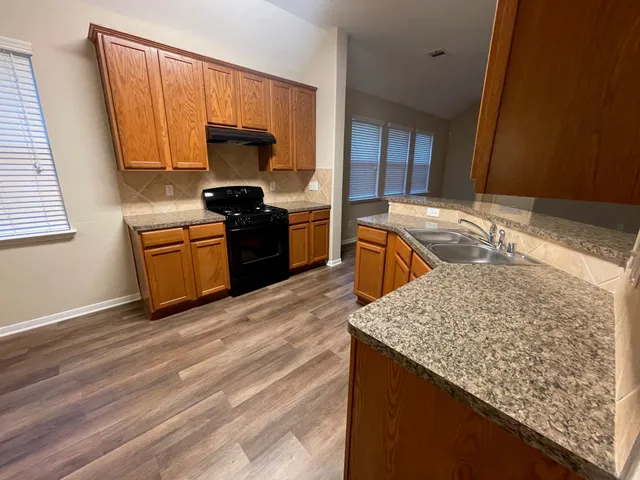 a kitchen with granite countertop wooden cabinets and a sink