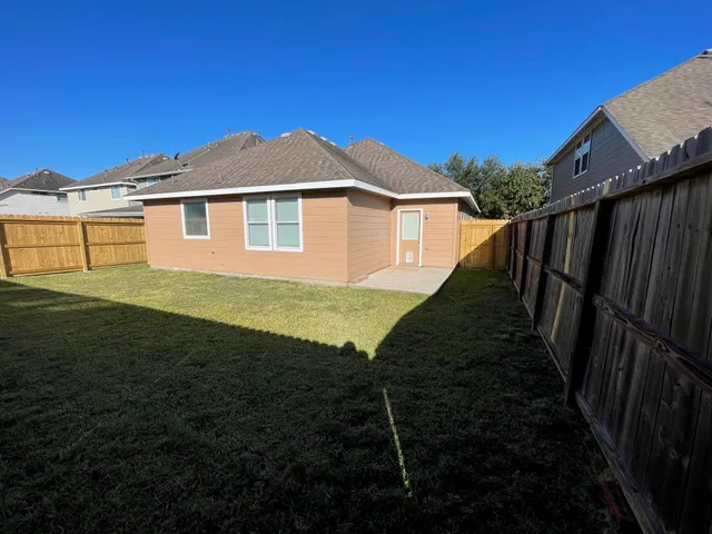 a view of a yard in front of a house with wooden fence