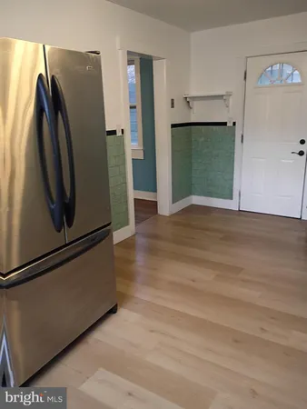 a view of a refrigerator in kitchen and an empty room