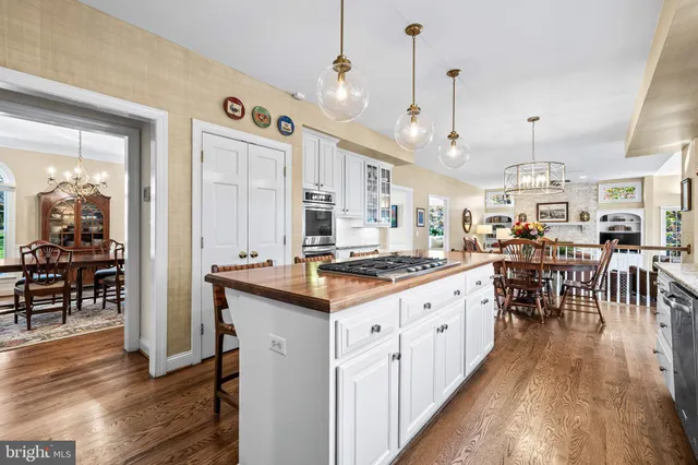 a kitchen with stainless steel appliances granite countertop wooden floor window and chairs