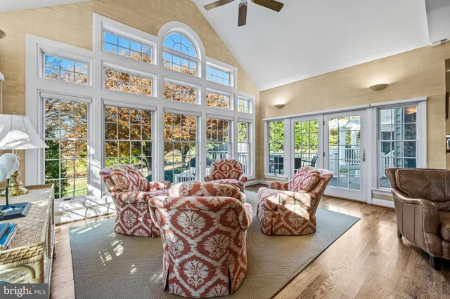 a living room with furniture large windows and wooden floor