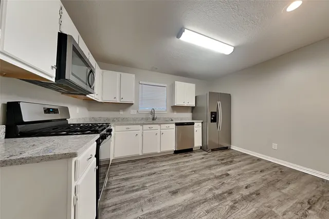 a kitchen with stainless steel appliances granite countertop a stove a sink and a refrigerator