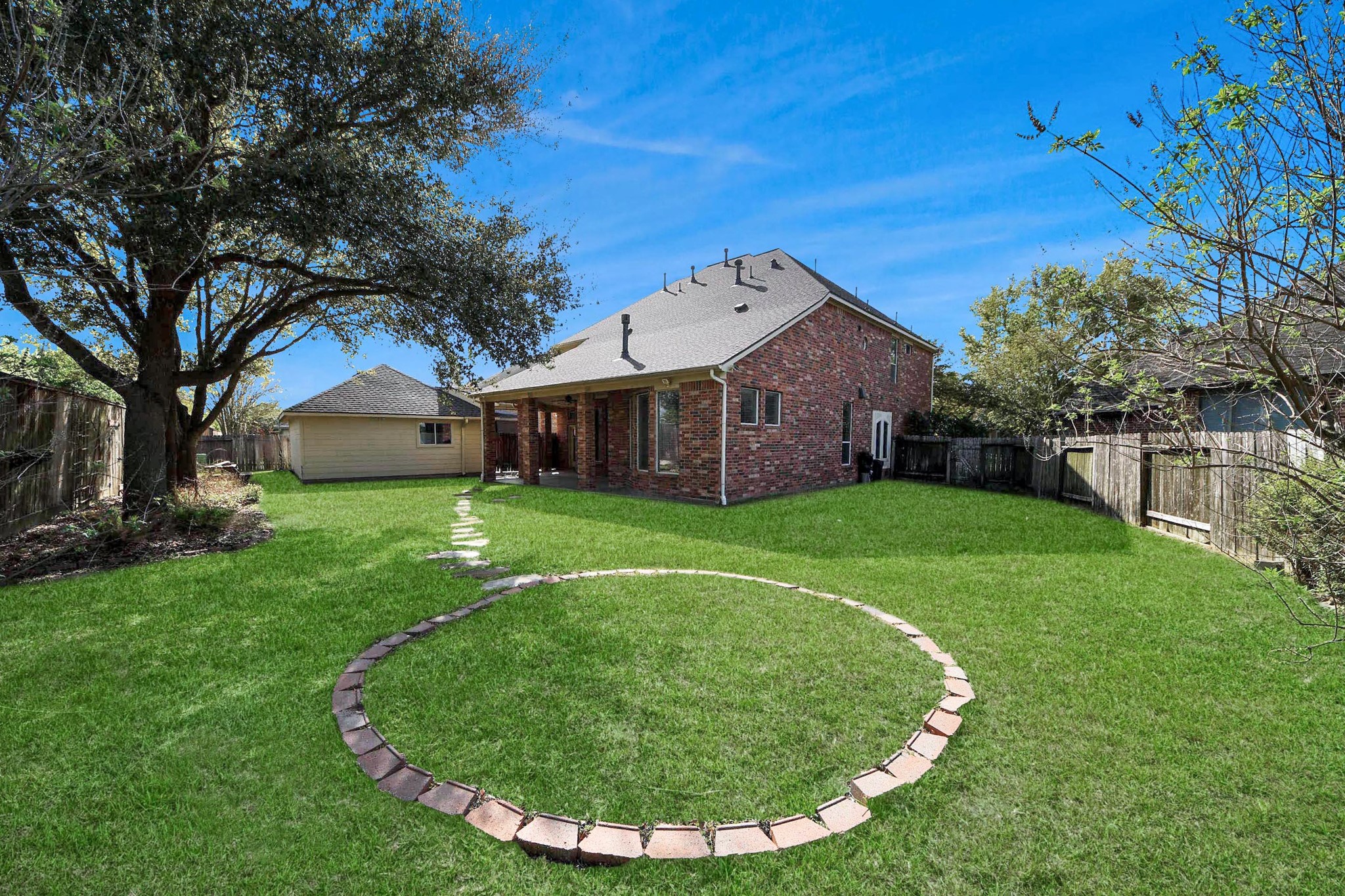 17618 Raven Canyon Lane Houston, TX 77095 - Photo 40 of 45 A tranquil backyard featuring lush green grass, a well-maintained lawn, and a stylish stone path, perfect for outdoor enjoyment.