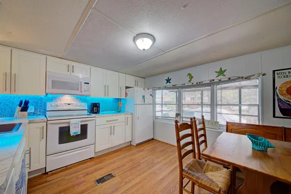 a kitchen with stainless steel appliances a white table chairs and a refrigerator
