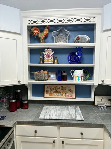 a kitchen with granite countertop white cabinets and black appliances