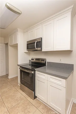 a kitchen with granite countertop white cabinets and stainless steel appliances