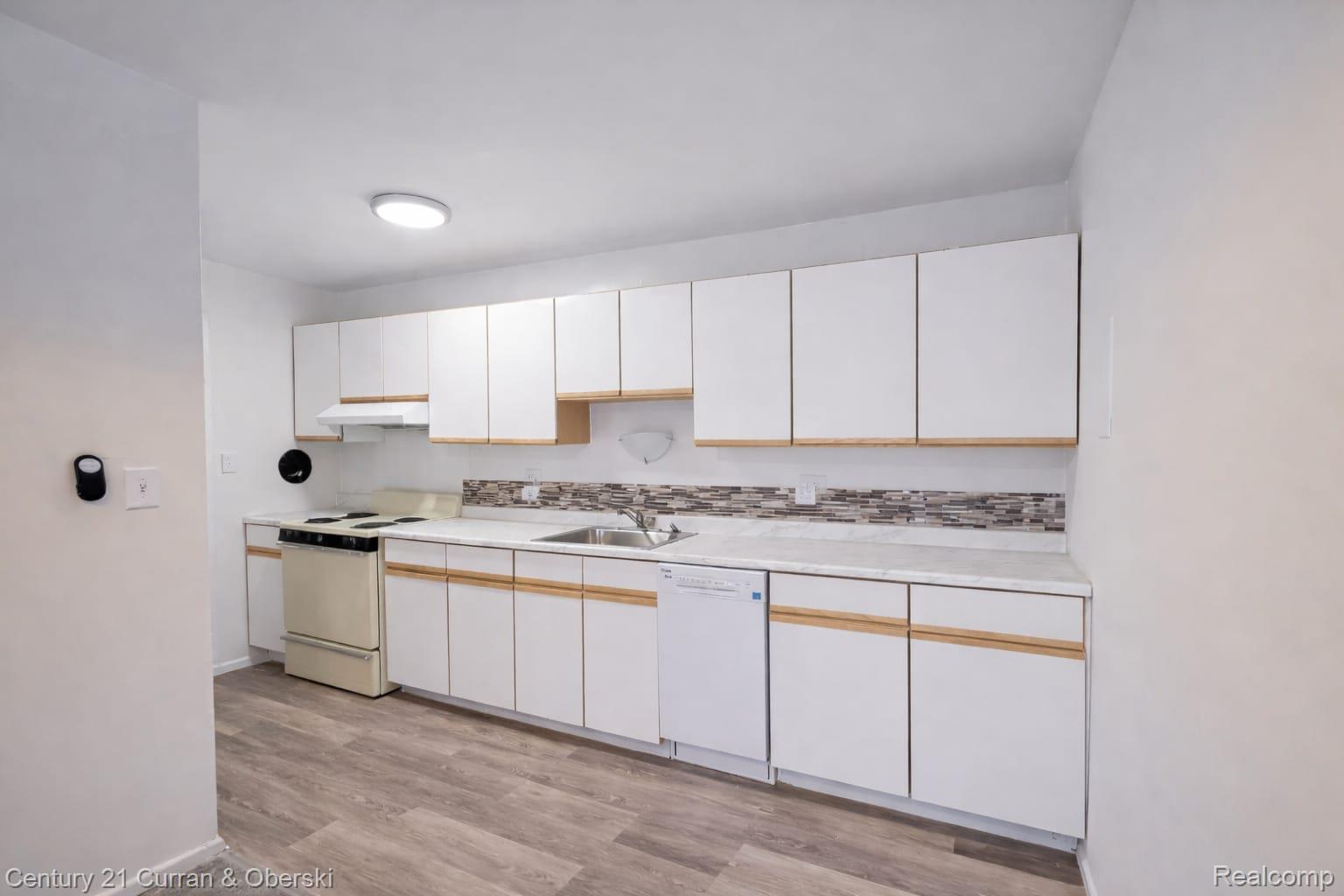 6035 Southfield Road, Unit 12 Detroit, MI 48228 - Photo 5 of 10 Kitchen with light countertops, white appliances, light wood-type flooring, and white cabinetry