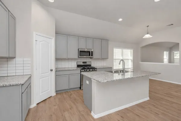 a kitchen with kitchen island granite countertop a sink stove and refrigerator