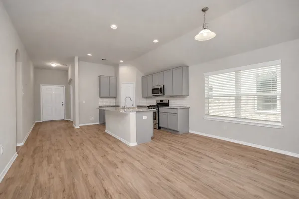 a view of kitchen with granite countertop refrigerator oven sink and white cabinets with wooden floor