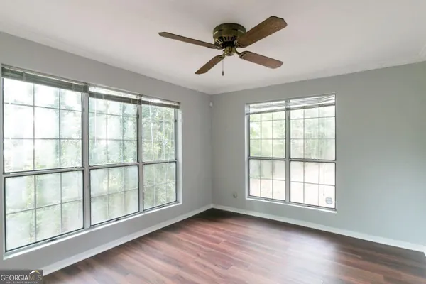 a view of an empty room with wooden floor and a window