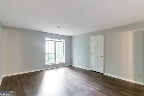 a view of an empty room with wooden floor and window
