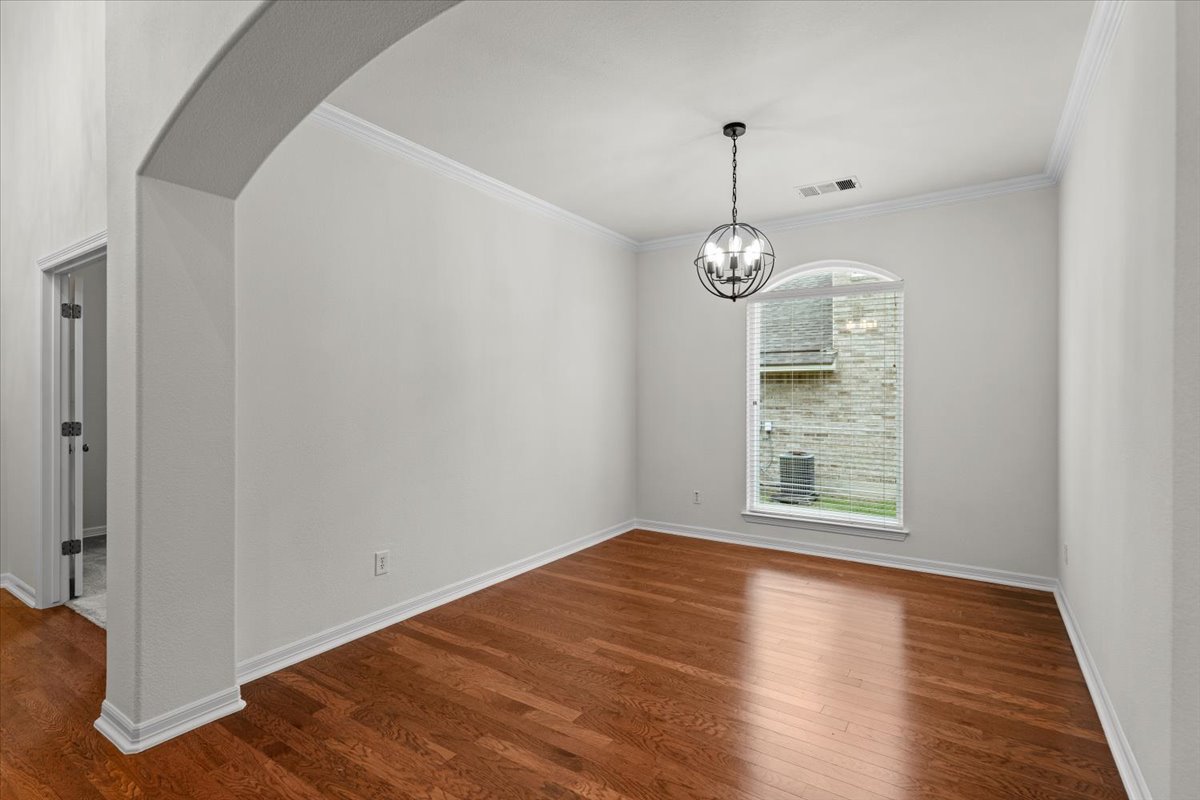 2304 Village View Loop Pflugerville, TX 78660 - Photo 19 of 40 Elegant hardwood flooring grounds a formal dining room with a refined arched entry and crown molding.