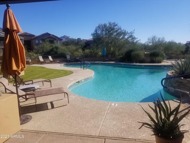 a view of a swimming pool with lawn chairs under an umbrella