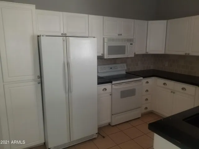 a kitchen with white cabinets and white appliances