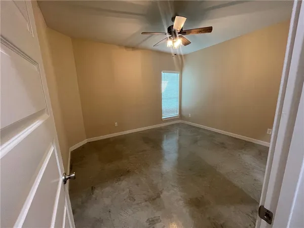 an empty room with a chandelier fan and windows