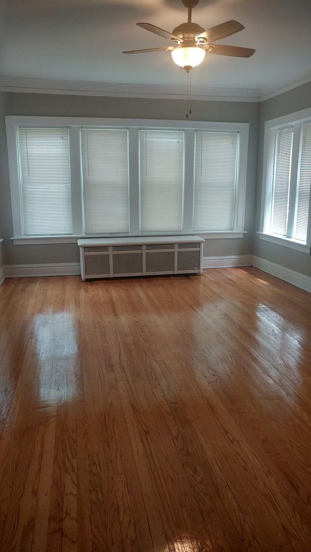 7412 South Prairie Avenue, Unit 1F Chicago, IL 60619 - Photo 3 of 6 an empty room with wooden floor chandelier and windows