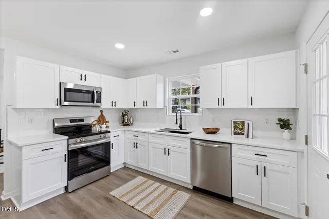 a kitchen with white cabinets stainless steel appliances and sink