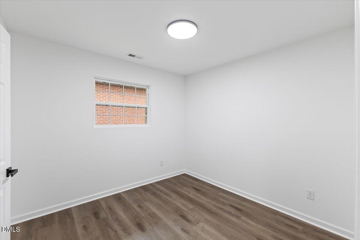 606 Cecil Street Durham, NC 27707 - Photo 16 of 25 an empty room with wooden floor and windows