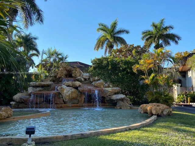 a view of a house with a yard and palm trees
