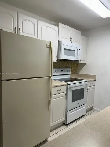 a kitchen with cabinets and white stainless steel appliances