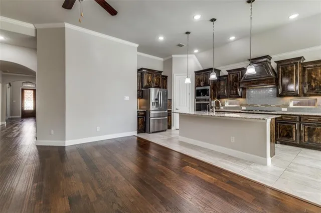 a kitchen with stainless steel appliances granite countertop a sink a stove and a wooden floors